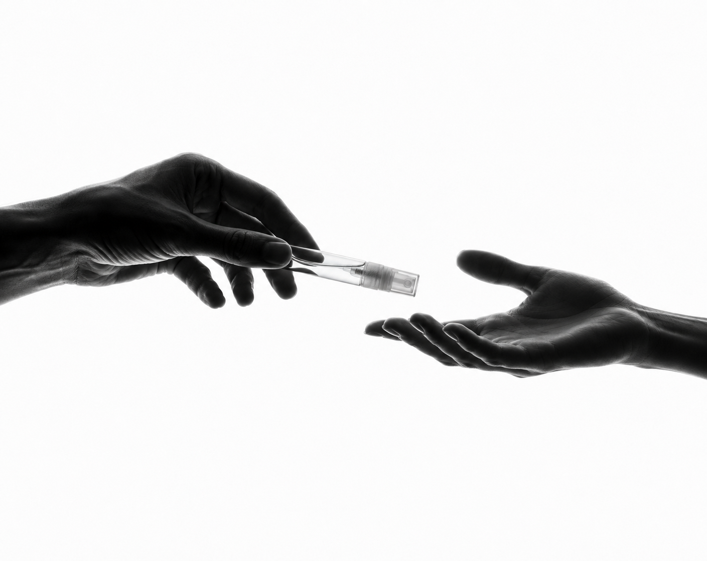 Una persona entrega un decant de perfume sobre una mano abierta